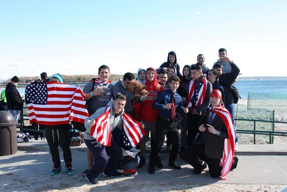 Some of the students wrapped in large American flags and smiling bravely before jumping and diving in the Sound
