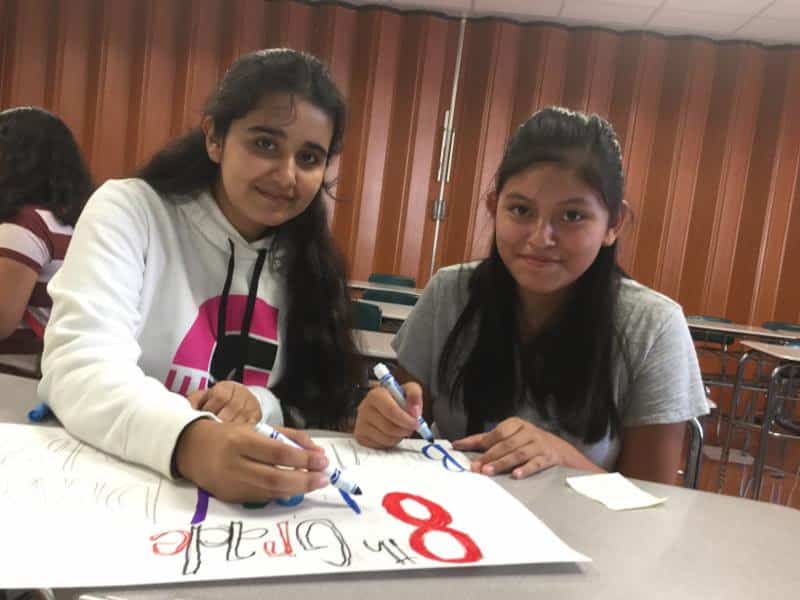 Isaac E. Young eighth graders Emelien Perez (left) and Lesly Paccha work on food drive posters.