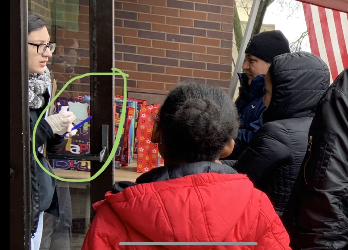 Worker offering to squirt hand sanitizer into hands of clients